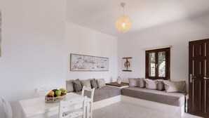 Een moderne woonkamer met een witte bank, een eettafel met stoelen en een decoratieve lamp.