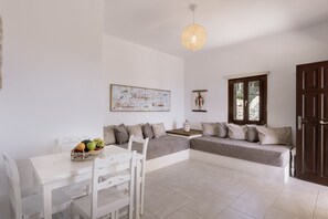 A modern living room with a white sofa, a dining table with chairs, and a decorative light fixture. - One bedroom Apartment-Sleeps 4 -Sea View-Parking (Pyrgos)