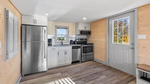 Une cuisine moderne dotée d’appareils électroménagers en acier inoxydable, de lambris en bois et d’une grande fenêtre.