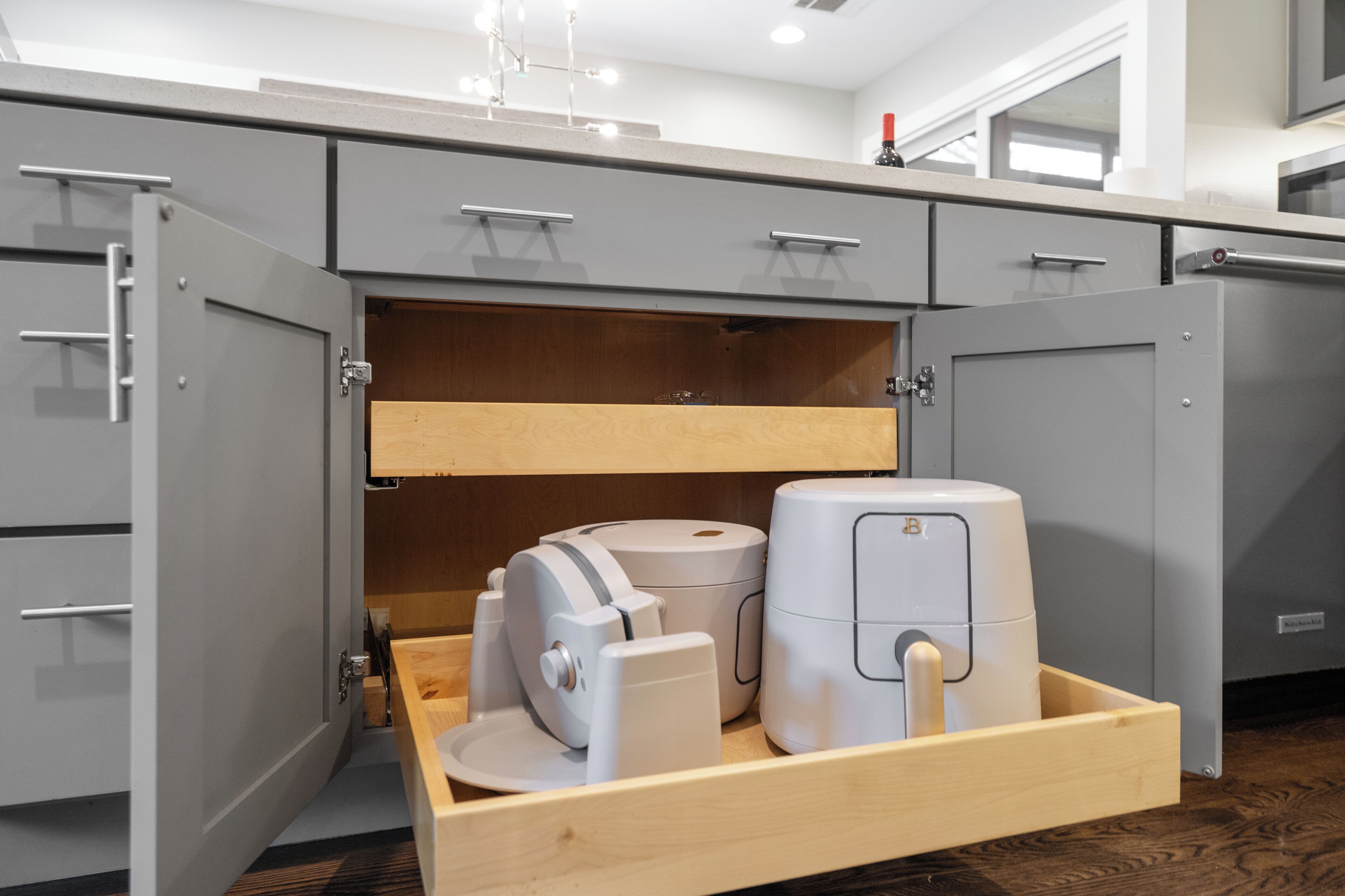 Eine Küche mit grauen Schränken, einer Holz Arbeitsplatte und einer eingebauten Schubladenleiste mit Küchengeräten.