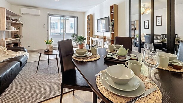 Een moderne woonkamer met een eethoek, met een bank, een salontafel, een televisie en een boekenkast.