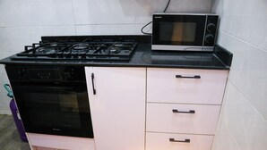 Une cuisine compacte équipée d’une cuisinière à gaz, d’un four, d’un four à micro-ondes et d’un petit plan de travail.