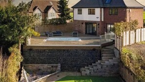 Ein modernes Haus mit Schwimmbecken, einer Steinmauer und einer Treppe, die zu der oberen Etage führt.