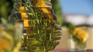 Et gennemsigtigt glas med lagdelt design, fyldt med grønne urter og gule blomster, placeret på en træoverflade.