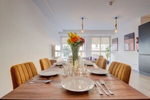 A dining area with a wooden table set for four, surrounded by yellow chairs, with a vase of flowers in the center. - Kuya Suite No.1 / Central / Terrace (Swieqi)