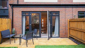 A brick building with a patio area featuring outdoor seating and a wooden fence.