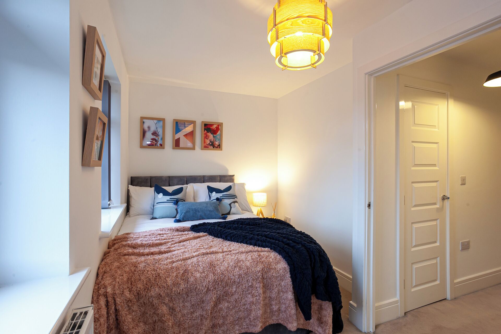 A bedroom with a bed, a bedside lamp, and a door.