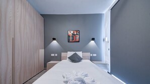 Moderni hotellihuone, jossa on suuri sänky, puinen vaatekaappi ja taulu seinällä.