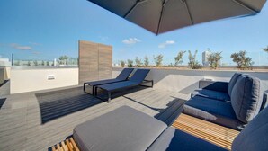 Een terras op het dak met een loungegedeelte, een houten dek en uitzicht op de stad.