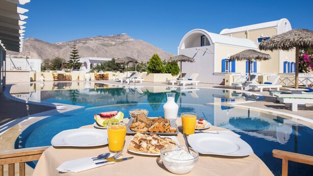 Desayuno junto a la piscina, con una mesa, platos y una variedad de comida y bebidas.