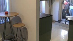 Una cocina moderna con una isla central, dos taburetes de bar y un ventanal con persianas.