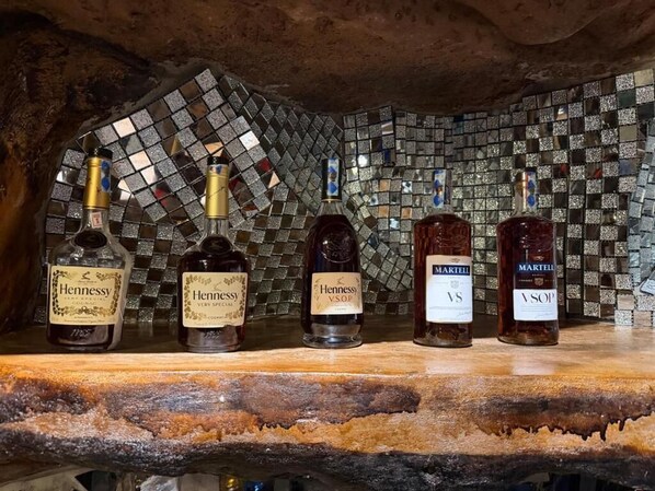 Four bottles of Hennessy VSOP on a bar counter with a mosaic tile backsplash. - Mawimbi Jiko Hotel Taveta (Taveta)