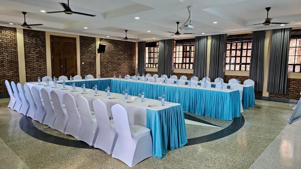 A conference room with long tables, white chairs, and blue tablecloths.