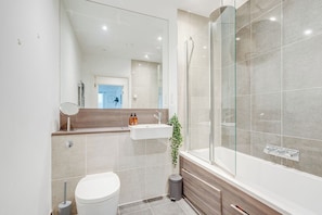 A modern bathroom with a glass-enclosed shower, a white sink, and a toilet. - Battersea 2-Bed Apt, Sleeps 4 with WiFi (London)