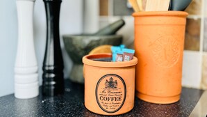 A kitchen counter with a coffee grinder, pepper shakers, and a coffee pot. - Ulverston Cozy Cottage Retreat (Ulverston)