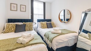 Ett hotellrum med två sängar, en stor spegel och ett fönster med gardiner.