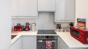 Ett modernt kök med vita skåp, en röd mikrovågsugn, en gasspis och en inbyggd ugn.