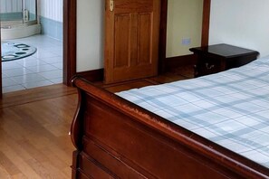 Une chambre à coucher avec un lit en bois, une petite table de chevet et une porte donnant sur une autre pièce.