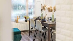 En matplats med ett bord för fyra personer, stolar, ett fönster med persienner och ett element.