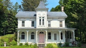 Una casa a due piani con una torre centrale, finestre simmetriche e un portico.