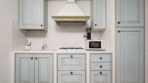 A kitchen with light blue cabinets, a white tiled backsplash, a microwave, and a gas stove. - Holiday Home 'Trilo Stazzu' with Private Terrace, Private Garden and Air Conditioning (San Teodoro)