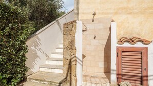 A stone staircase leading to a door with a tiled wall and a tiled roof above. - Holiday Home 'Trilo Stazzu' with Private Terrace, Private Garden and Air Conditioning (San Teodoro)