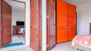 A hotel room with a bed, a television, and a wooden door. - Holiday Home 'Trilo Stazzu' with Private Terrace, Private Garden and Air Conditioning (San Teodoro)
