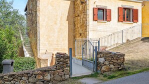 A two-story building with a stone facade, a metal gate, and a staircase leading to the upper floor. - Holiday Home 'Trilo Stazzu' with Private Terrace, Private Garden and Air Conditioning (San Teodoro)