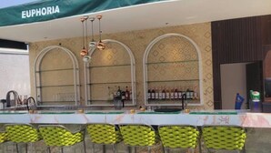 Zona de bar con toldo verde que dice 'EUPHORIA', taburetes y una pared con diseño.