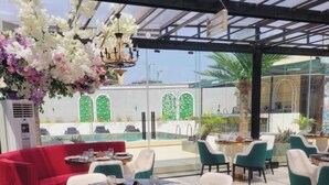 Un restaurante con mesas redondas, sillas color turquesa y un sofá rojo.