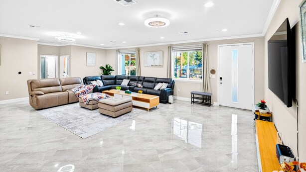 A spacious living room with a beige sofa, a black leather sectional, and a wooden coffee table. - Spacious 9BR Home + Parking + Near DTLA #TravelSGV (Avocado Heights)