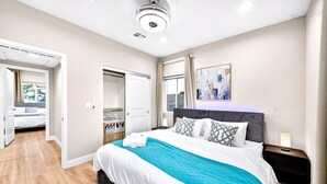 A modern hotel room with a large bed, a nightstand, a painting on the wall, and a view of the outside. - Spacious 9BR Home + Parking + Near DTLA #TravelSGV (Avocado Heights)