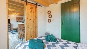 A bedroom with a bed, a green door, and a wooden ceiling.