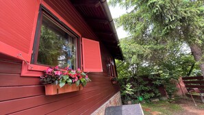 A red wooden house with a window and a flower box.