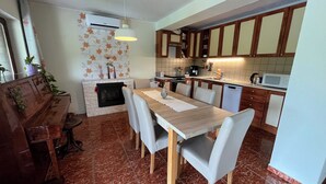 A kitchen with a dining table, chairs, a fireplace, cabinets, and a microwave.