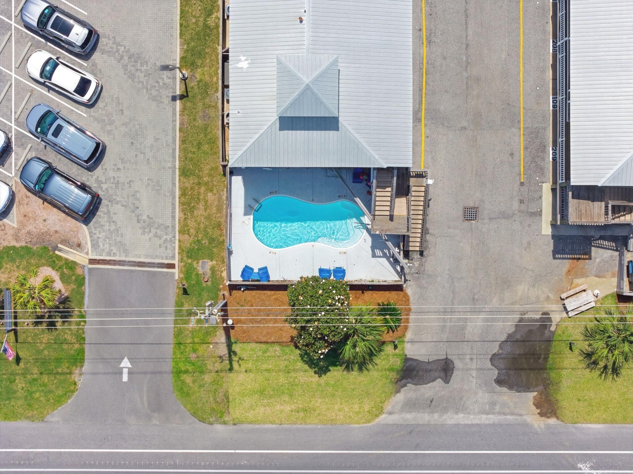 An aerial view of a house with a swimming pool, a garage, and a driveway.