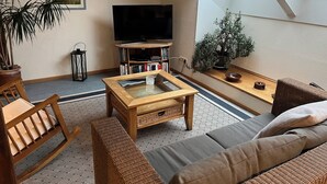 A cozy living room with a TV, bookshelf, and a large window. - Rural idyll on the edge of the village with sweeping views, not far from Kappeln (Stoltebüll)