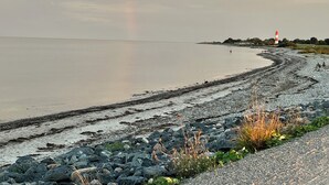 A beach with a rainbow, rocky shore, and a lighthouse in the distance. - Rural idyll on the edge of the village with sweeping views, not far from Kappeln (Stoltebüll)
