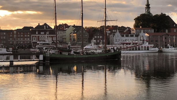 A harbor with a large sailing ship docked, surrounded by buildings and a church spire in the background. - Rural idyll on the edge of the village with sweeping views, not far from Kappeln (Stoltebüll)