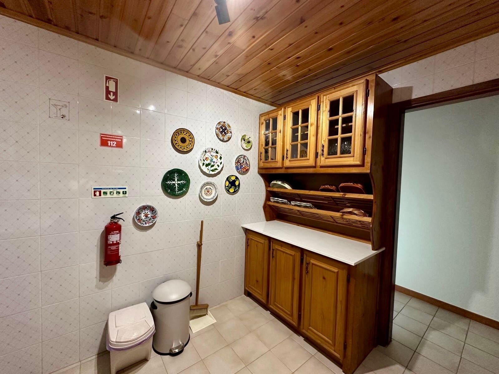 Una cucina con mobili in legno, un piano di lavoro bianco e diverse piastre decorative appese al muro.