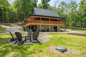 A cabin with a deck, outdoor seating, and a covered area.