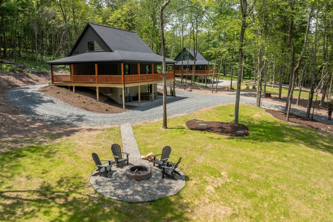 A cabin with a deck, surrounded by a forest.