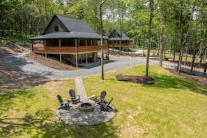 A cabin with a deck, surrounded by a forest.