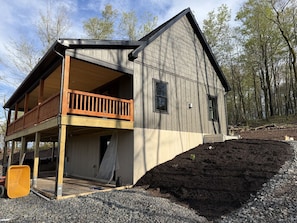 Une maison à deux étages avec un balcon, un revêtement extérieur en bois et une allée gravillonnée.