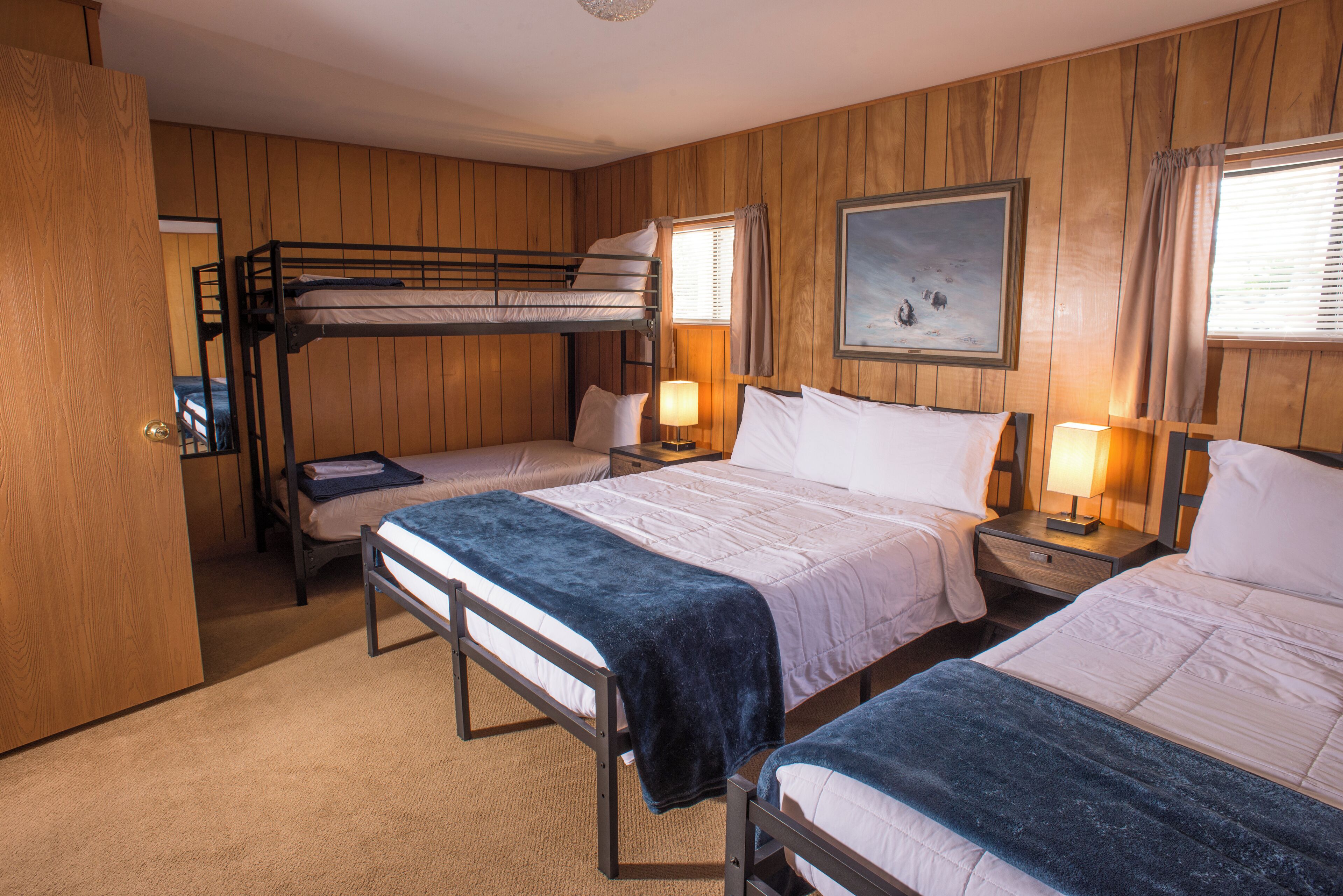 A room with bunk beds, a painting on the wall, and a door.