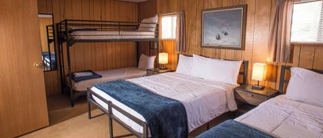 A room with bunk beds, a painting on the wall, and a door.
