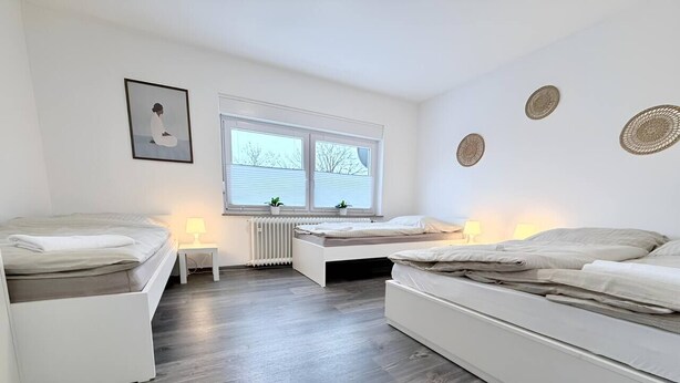 Ein Schlafzimmer mit zwei Betten, einem Heizkörper, einem Fenster mit Jalousien und Wanddekoration.