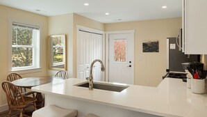 A modern kitchen with a central island, white cabinetry, and a large window. - Serene Fairview Escape (Fairview)