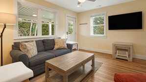 A living room with a grey sofa, wooden coffee table, and a TV mounted on the wall. - Serene Fairview Escape (Fairview)