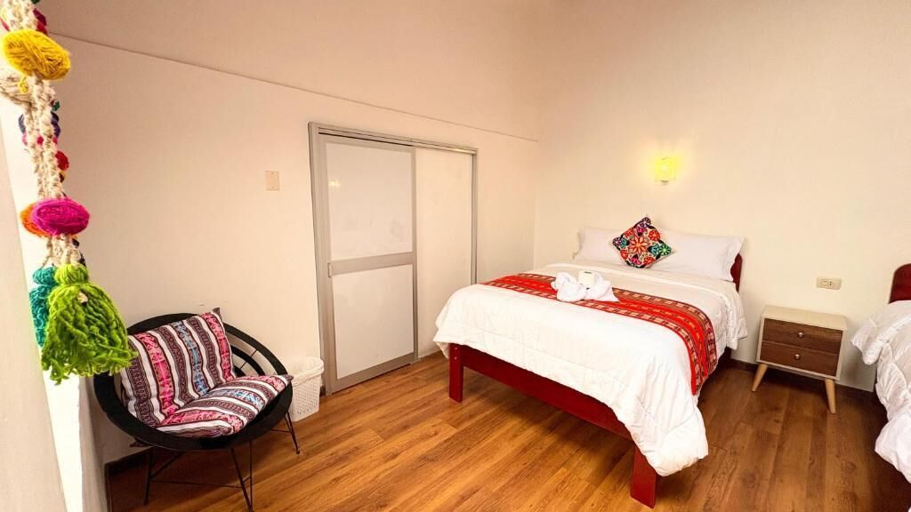 Een slaapkamer met een bed, een stoel, een nachtkastje en een wandlamp.
